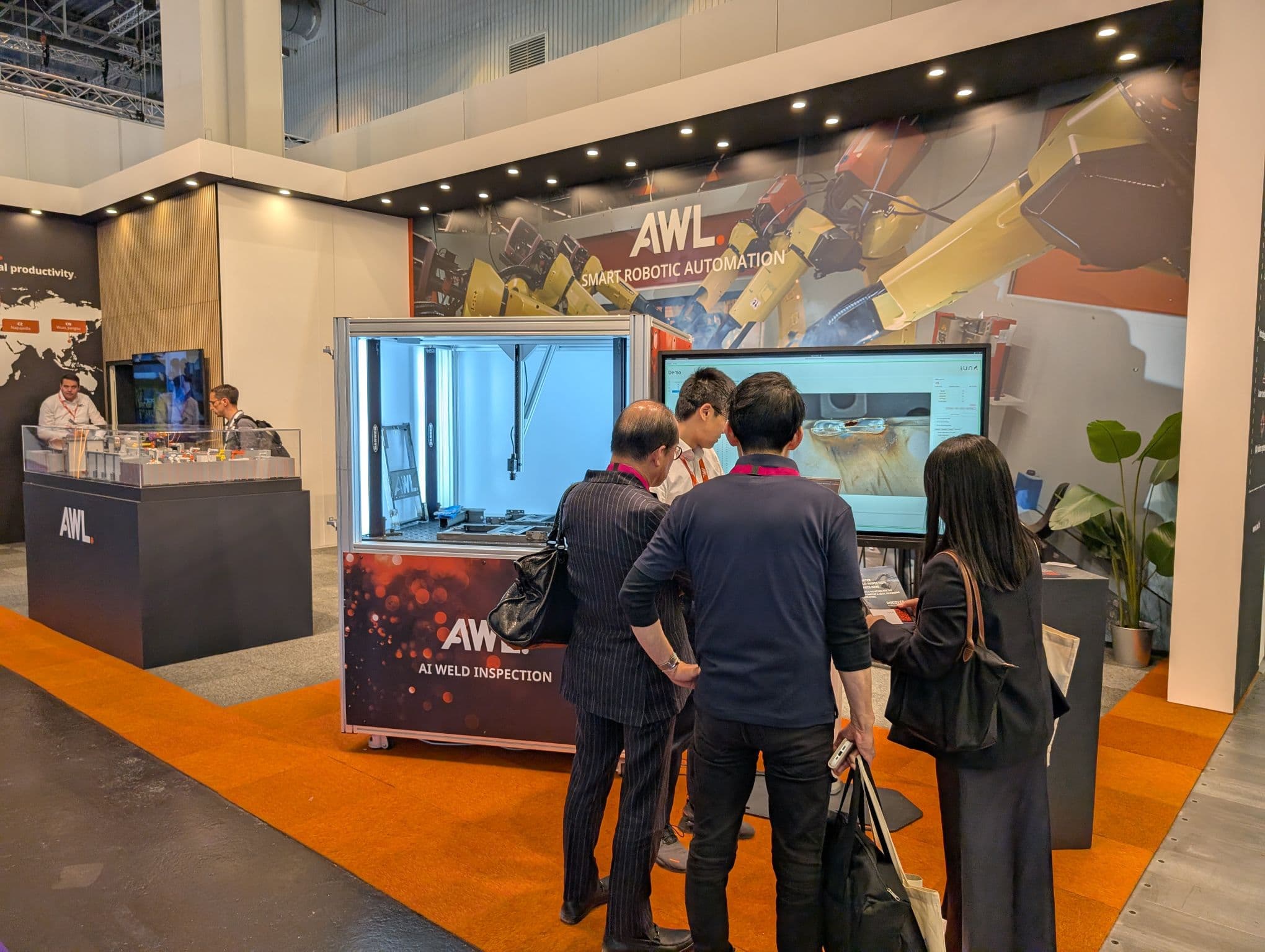 Visitors examining the IUNA AI Weld Seam Scanner demonstration at the AWL booth