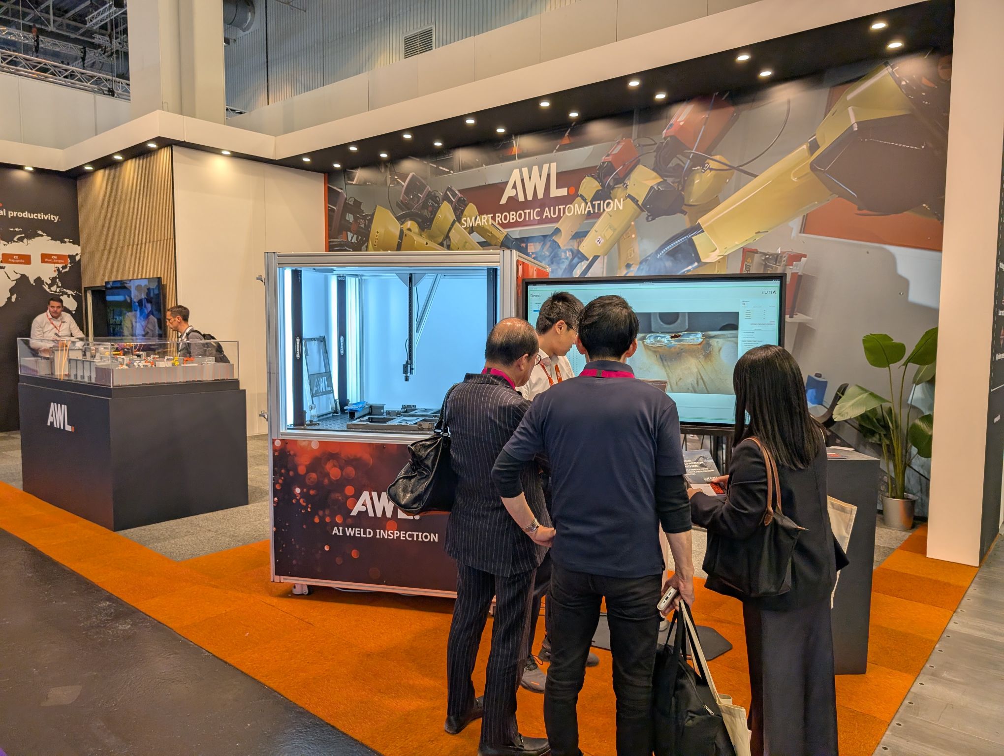 Visitors examining the IUNA AI Weld Seam Scanner demonstration at the AWL booth